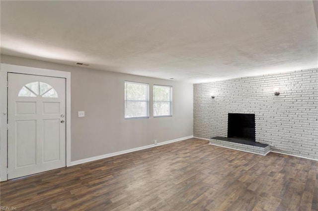 entryway with dark wood-type flooring, a brick fireplace, and brick wall