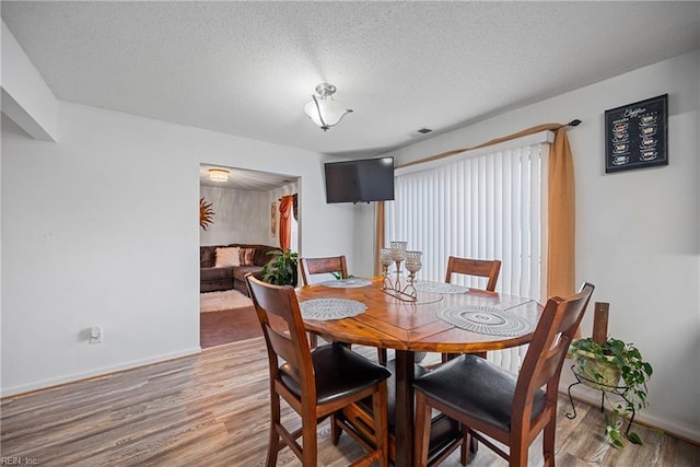 dining area featuring a textured ceiling and hardwood / wood-style floors