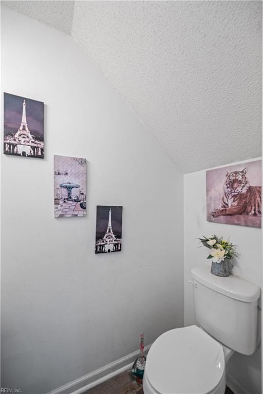 bathroom featuring a textured ceiling, toilet, and lofted ceiling