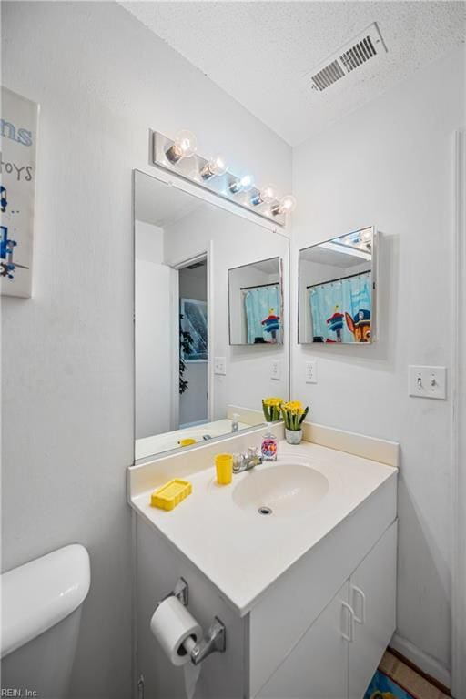 bathroom featuring a textured ceiling, toilet, and vanity