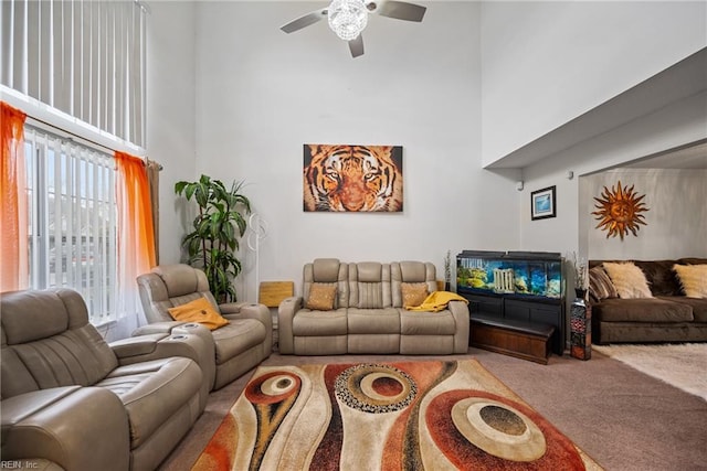 living room featuring carpet floors, ceiling fan, and a high ceiling