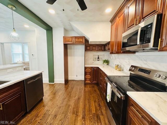 kitchen featuring light stone countertops, appliances with stainless steel finishes, tasteful backsplash, hanging light fixtures, and dark hardwood / wood-style floors