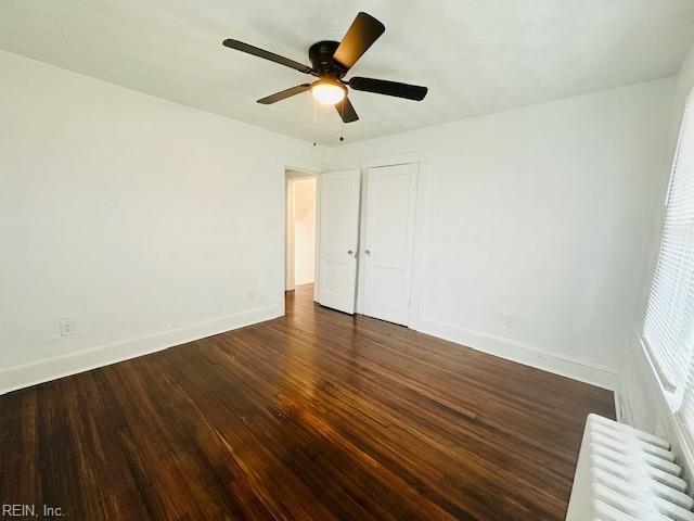 unfurnished bedroom featuring a closet, ceiling fan, radiator, and dark hardwood / wood-style floors