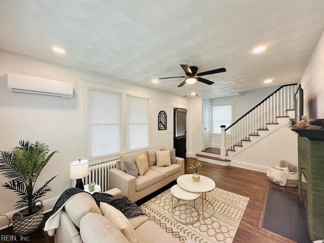 living room with a healthy amount of sunlight, a wall mounted air conditioner, dark hardwood / wood-style floors, and ceiling fan