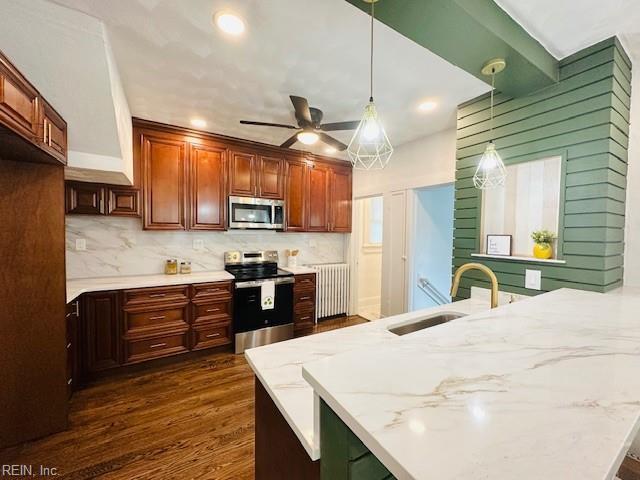 kitchen featuring ceiling fan, hanging light fixtures, sink, radiator, and stainless steel appliances