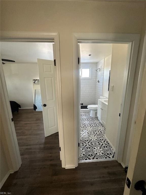 bathroom featuring hardwood / wood-style floors, toilet, tiled shower, and vanity