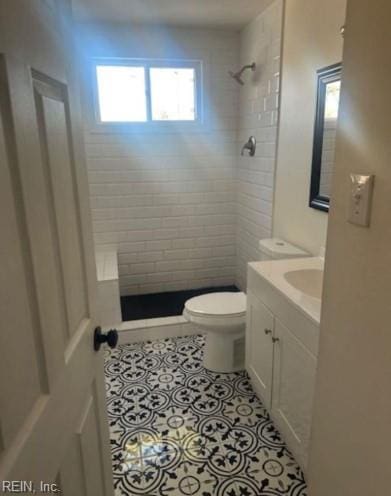 bathroom with vanity, toilet, a tile shower, and tile patterned flooring