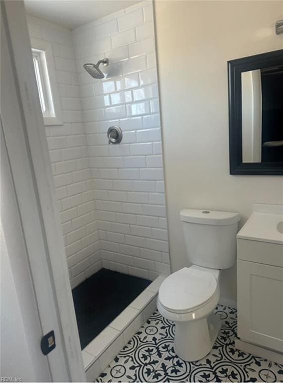 bathroom with tiled shower, toilet, and vanity