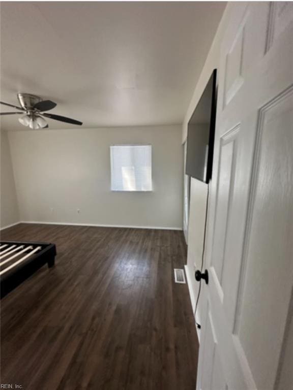 empty room with ceiling fan and dark hardwood / wood-style flooring