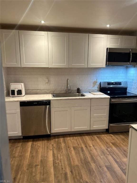 kitchen featuring white cabinets, appliances with stainless steel finishes, decorative backsplash, sink, and light hardwood / wood-style flooring