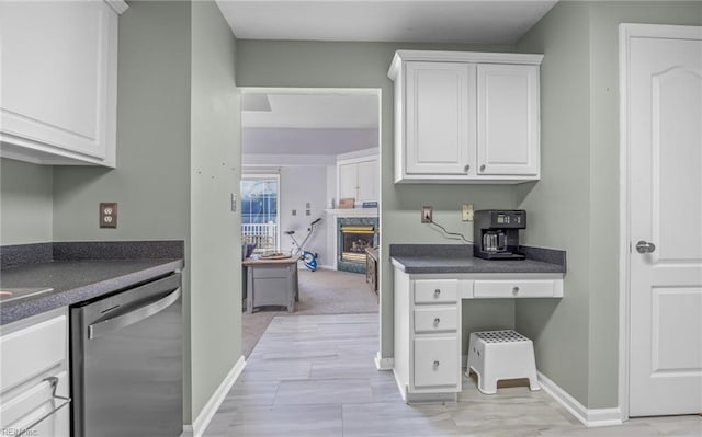 kitchen with a premium fireplace, white cabinetry, and stainless steel dishwasher