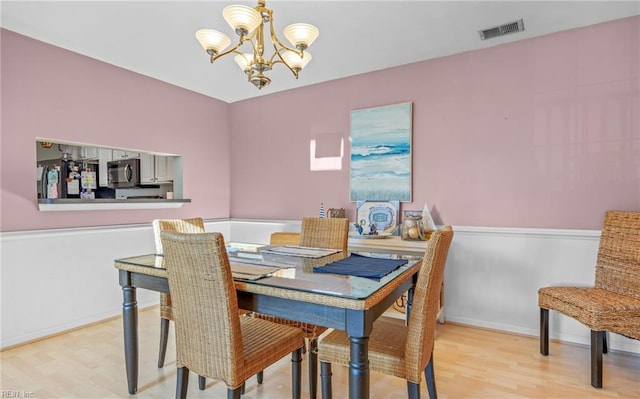 dining space with light hardwood / wood-style flooring and a notable chandelier