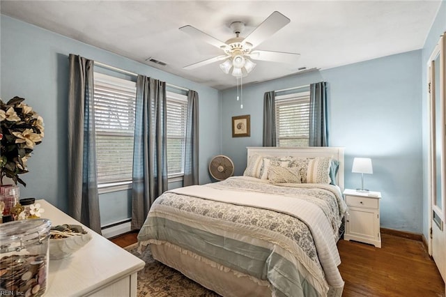 bedroom with ceiling fan, baseboard heating, and dark hardwood / wood-style floors