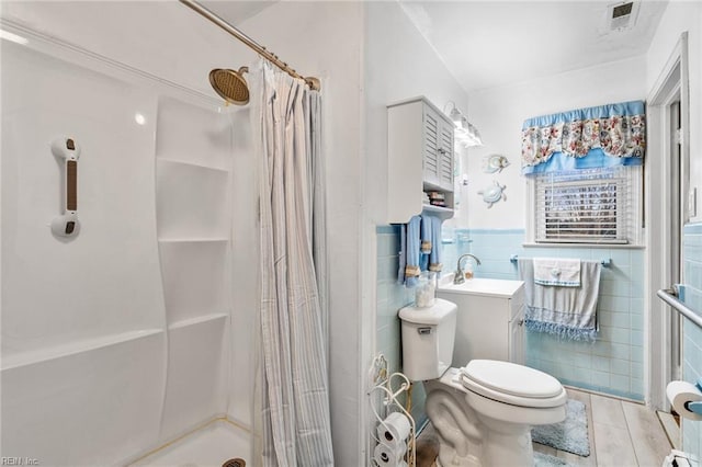 bathroom with tile patterned floors, tile walls, toilet, walk in shower, and vanity