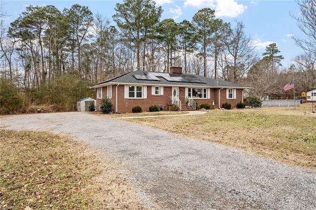 ranch-style house with solar panels, a front yard, and a storage unit