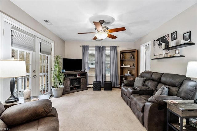 living room with a healthy amount of sunlight, light colored carpet, ceiling fan, and french doors