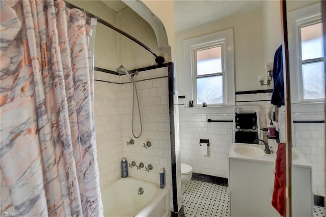 full bathroom featuring toilet, vanity, tile walls, and shower / tub combo with curtain