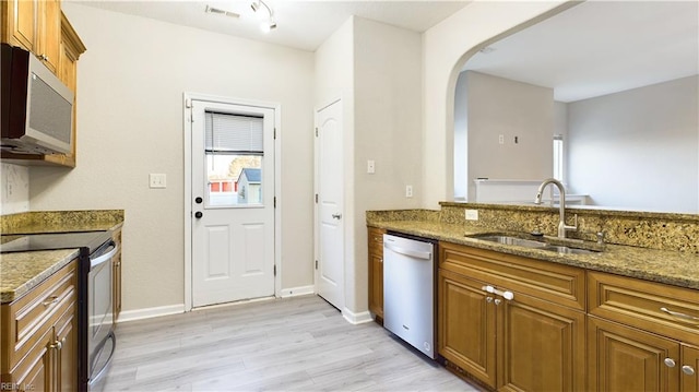 kitchen with light stone countertops, sink, stainless steel appliances, and light hardwood / wood-style flooring