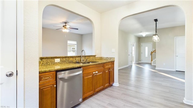 kitchen featuring ceiling fan, dishwasher, hanging light fixtures, stone counters, and sink