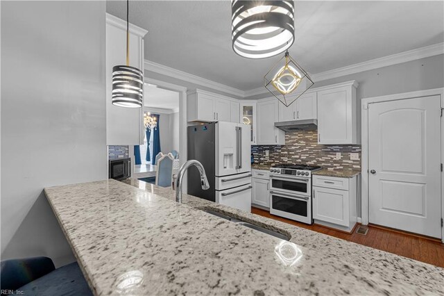 kitchen with white cabinets, double oven range, light stone counters, and white refrigerator with ice dispenser