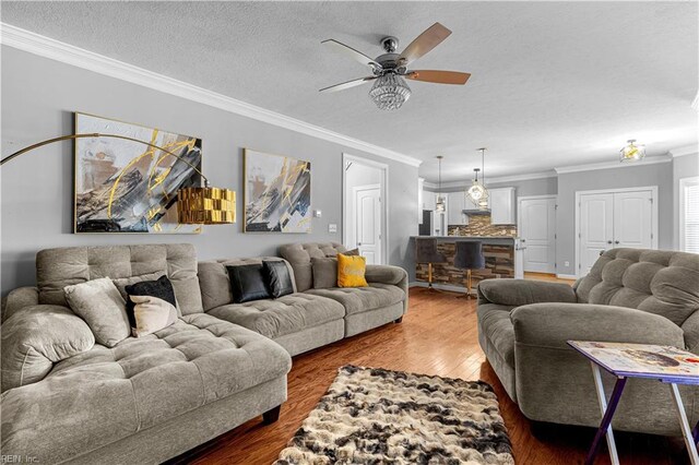 living room with ceiling fan, a textured ceiling, dark hardwood / wood-style floors, and crown molding