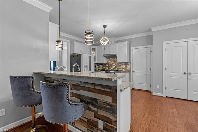 kitchen featuring kitchen peninsula, a kitchen breakfast bar, decorative light fixtures, white cabinets, and high quality fridge