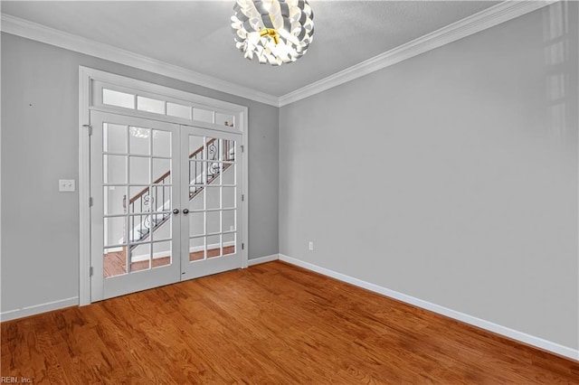 unfurnished room with wood-type flooring, crown molding, a chandelier, and french doors