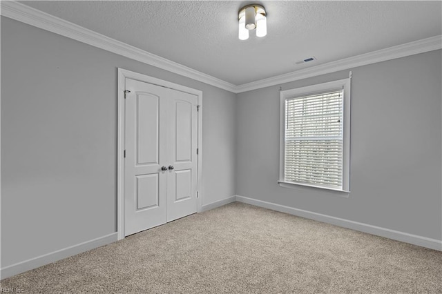 unfurnished bedroom featuring a closet, carpet, crown molding, and a textured ceiling