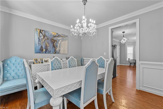 dining room with crown molding, wood-type flooring, and a chandelier