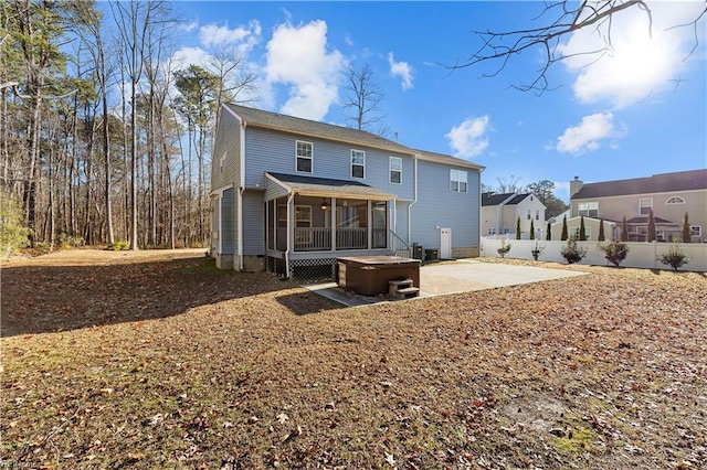 rear view of house featuring a sunroom, a patio, and a hot tub