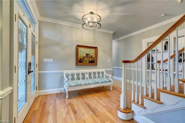 entrance foyer with crown molding, an inviting chandelier, and light hardwood / wood-style floors