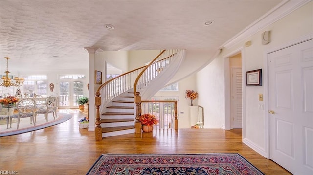 foyer entrance with french doors, an inviting chandelier, ornamental molding, and wood-type flooring