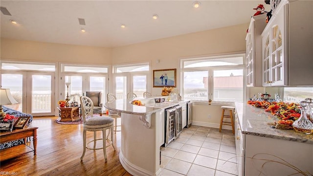 kitchen with light stone countertops, a breakfast bar, plenty of natural light, and kitchen peninsula