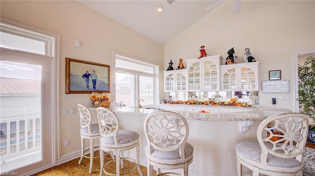 kitchen featuring vaulted ceiling, a kitchen bar, kitchen peninsula, and light hardwood / wood-style flooring