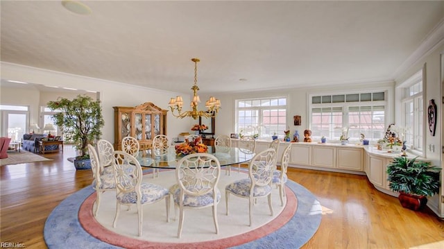 dining room with an inviting chandelier, crown molding, and light hardwood / wood-style flooring