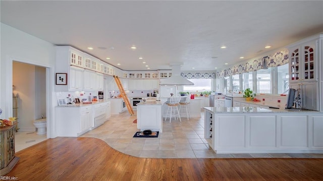 kitchen featuring light tile patterned floors, custom exhaust hood, white cabinets, and a center island