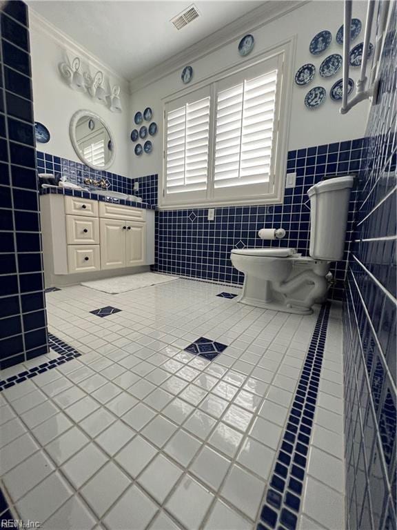 bathroom featuring toilet, vanity, tile walls, tile patterned floors, and ornamental molding