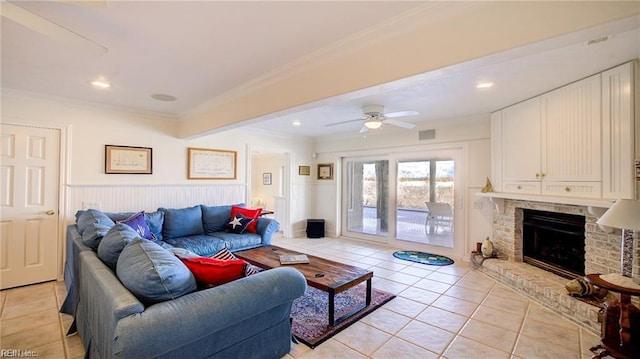 tiled living room with ceiling fan, crown molding, and a fireplace