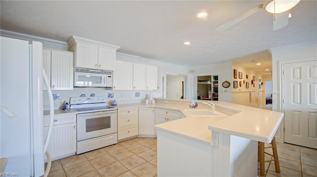 kitchen featuring white cabinets, a kitchen bar, sink, and white appliances