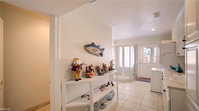 interior space featuring light tile patterned flooring, white cabinetry, crown molding, and sink