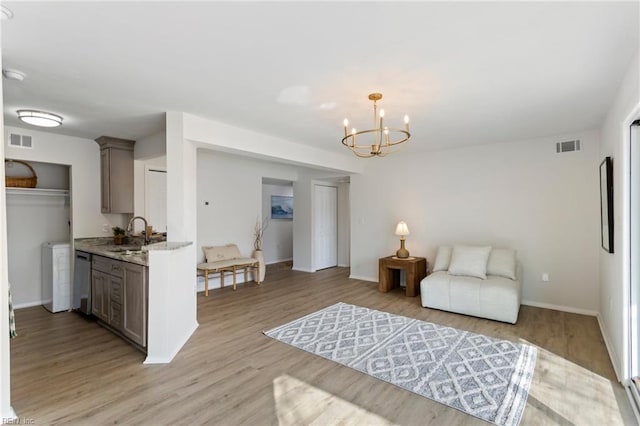 living room featuring washer / dryer, sink, light hardwood / wood-style flooring, and a notable chandelier