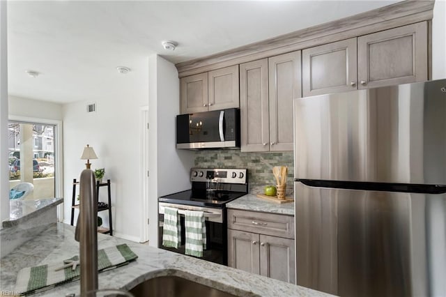 kitchen featuring appliances with stainless steel finishes, backsplash, and light stone counters