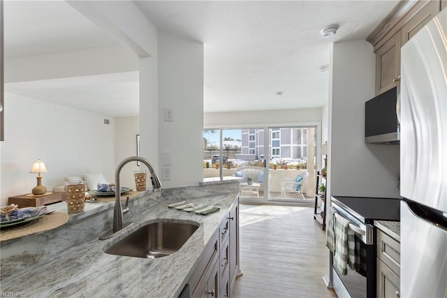 kitchen featuring electric stove, sink, refrigerator, light stone countertops, and light wood-type flooring