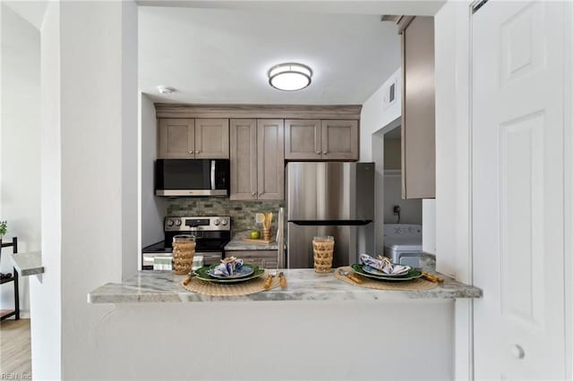 kitchen with appliances with stainless steel finishes, light stone counters, and decorative backsplash