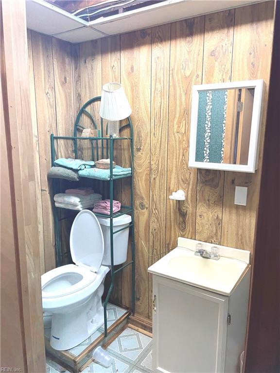 bathroom featuring toilet, vanity, and wood walls