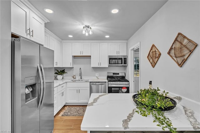 kitchen featuring appliances with stainless steel finishes, sink, light stone counters, and white cabinetry