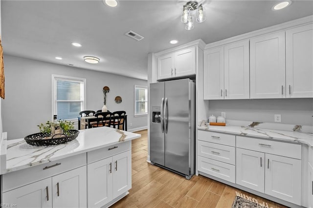 kitchen featuring light hardwood / wood-style floors, light stone counters, white cabinetry, and stainless steel fridge