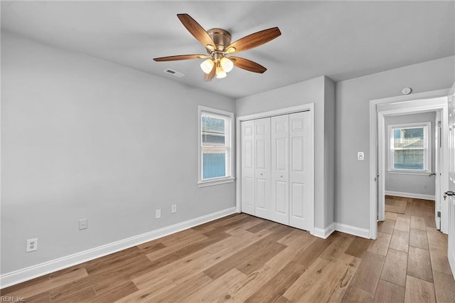 unfurnished bedroom featuring light wood-type flooring, ceiling fan, a closet, and multiple windows