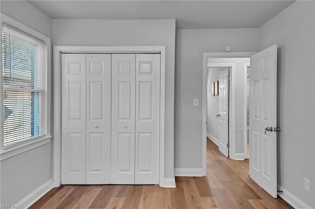 unfurnished bedroom featuring a closet, multiple windows, and light hardwood / wood-style flooring