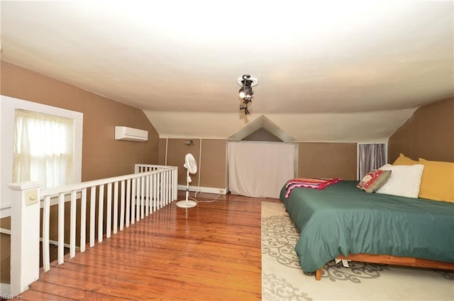 bedroom with an AC wall unit, hardwood / wood-style flooring, and lofted ceiling